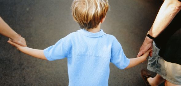 Two parents holding the hand of a child.