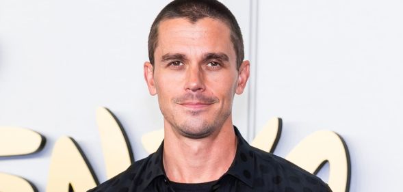 Antoni Porowski with a shaved head and black top and jacket.