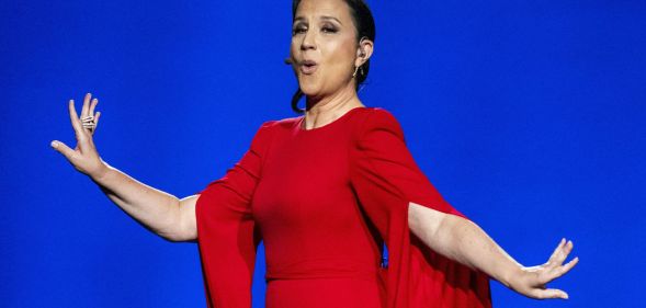 Eurovision Song Contest host Petra Mede in a red dress singing.