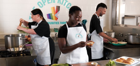 This is an image of three people preparing food in a kitchen
