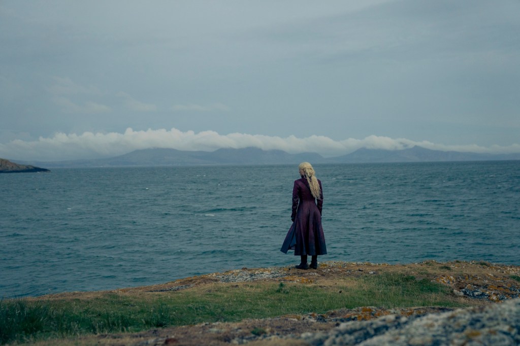 Emma D'Arcy as Queen Rhaenyra Targaryen in House of the Dragon season 2. Their character is looking out at the wide ocean.