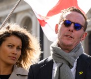 and Laurence Fox are standing together with an England flag blowing behind them