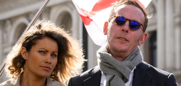 and Laurence Fox are standing together with an England flag blowing behind them