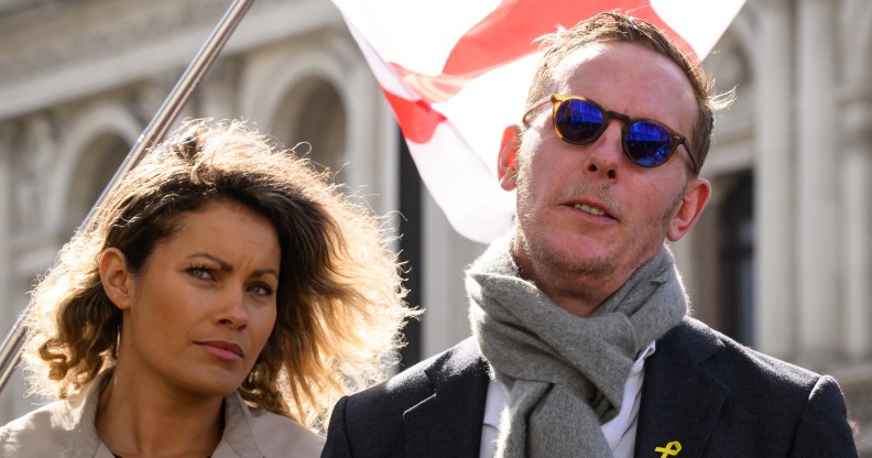 and Laurence Fox are standing together with an England flag blowing behind them