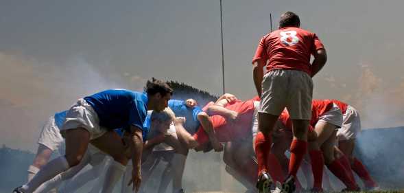 Rugby players in scrum on pitch, ground view