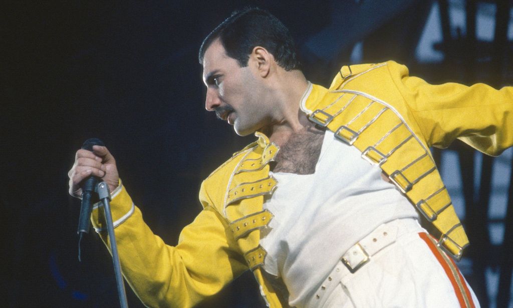 Freddie Mercury performing in his signature yelow jacket and white t-shirt.