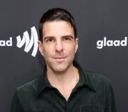 Zachary Quinto poses in a dark green shirt while on the GLAAD media award red carpet.