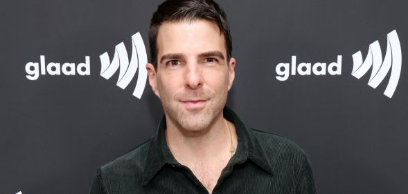 Zachary Quinto poses in a dark green shirt while on the GLAAD media award red carpet.