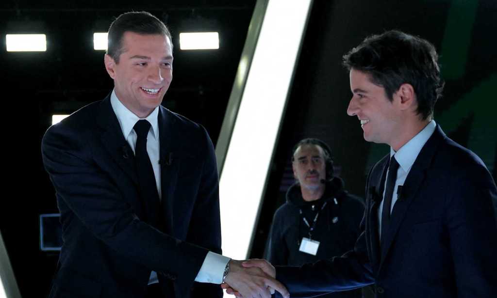 French far-right Rassemblement National (RN) party's President and leading candidate for the June 9 European union election Jordan Bardella (L) shakes hands with France's Prime Minister Gabriel Attal (R) as they arrive on the set for a debate.