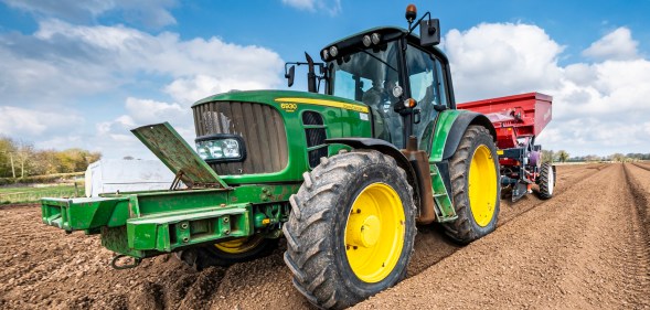 Mechanised planting of seed potatoes using a dewulf 3 row belt planter behind a John Deere tractor.