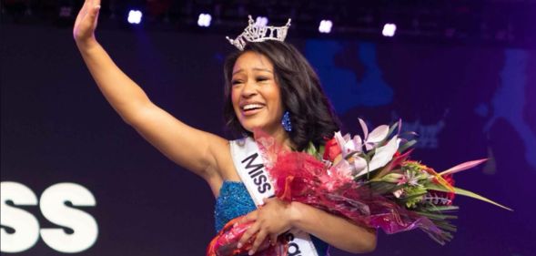 Alexis Smith, winner of the Miss Kansas beauty pageant wearing her crown, a sash, and holding a bouquet of flowers