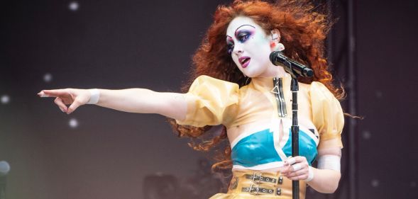 Chappell Roan performing in June 2024. She points off to the right of the stage.