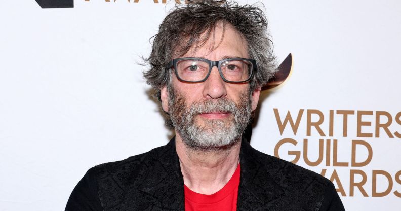 Neil Gaiman in a black blazer, red t-shirt, glasses.