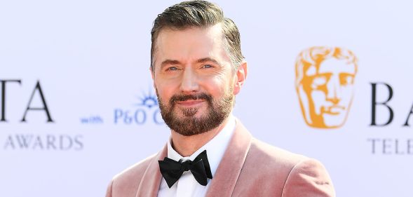 Richard Armitage in a pink suit and black bow tie