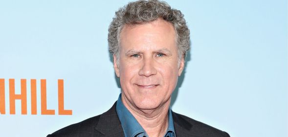 Will Ferrell smiles as he poses against a blue and orange red carpet background