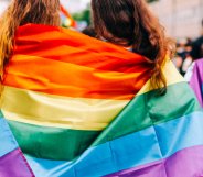 Two women wearing an LGBTQ+ Pride flag