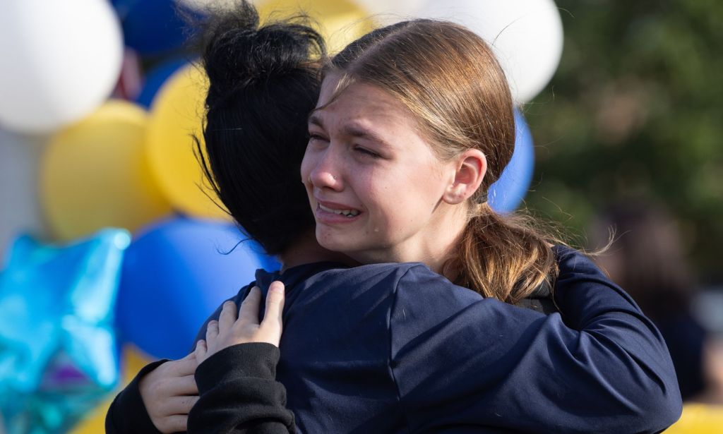 Two people embracing at a memorial dedicated to those killed in Winder, Georgia.