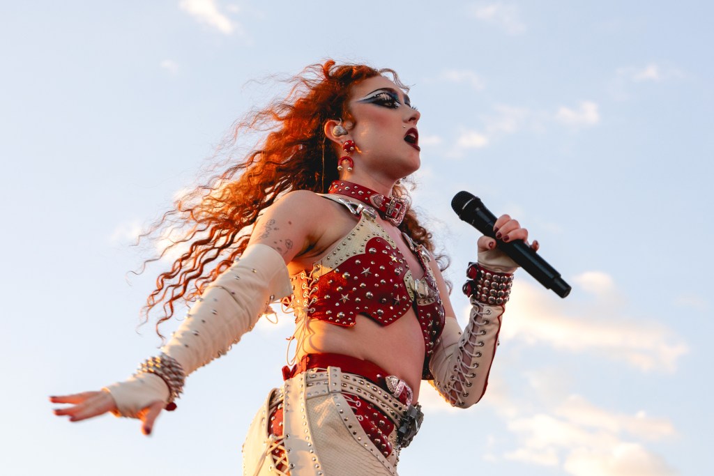 Chappell Roan performs onstage during weekend one, day three of the 2024 Austin City Limits Music Festival. Cowboy inspired long gloves and layered white nad red trousers.