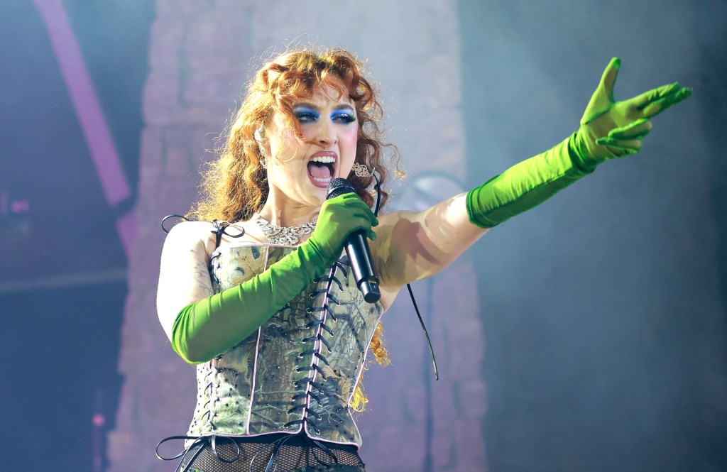 Chappell Roan performs at FirstBank Amphitheater, holding a gun hand gesture with bright green glovers and a floral corset