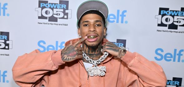 Rapper NLE Choppa in October 2024 wearing a orange hoodie grey cap and gold chain