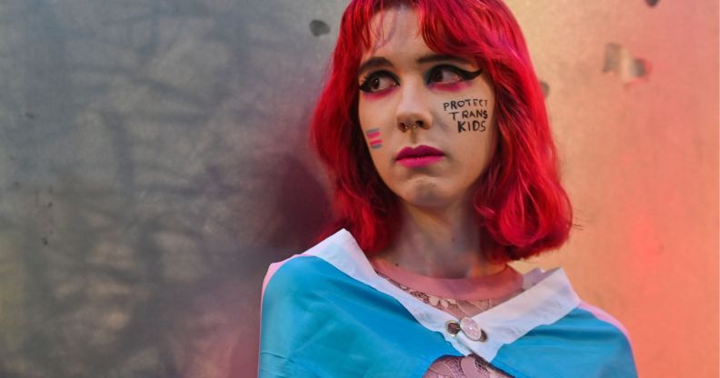 A person wearing a trans flag as a cape.