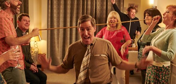 Gavin and Stacey still; family and friends surrounding Uncle Bryn (Rob Brydon) doing a limbo