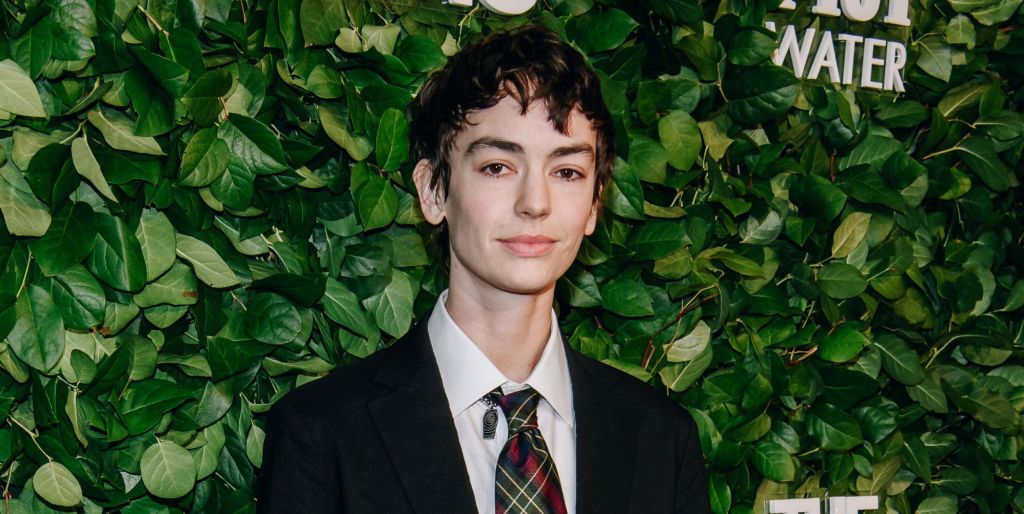 Jack Haven at a Vanity Fair red carpet event standing in front of greenery, wearing a black blazer and white shirt
