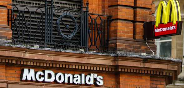 Pedestrians passing in front of a Mc Donald's restaurant on the main street of London, United Kingdom.