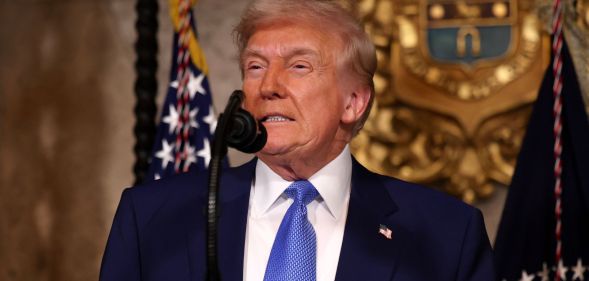 US President Donald Trump stands behind a microphone at a podium