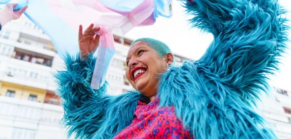 A person happily waving a trans flag.