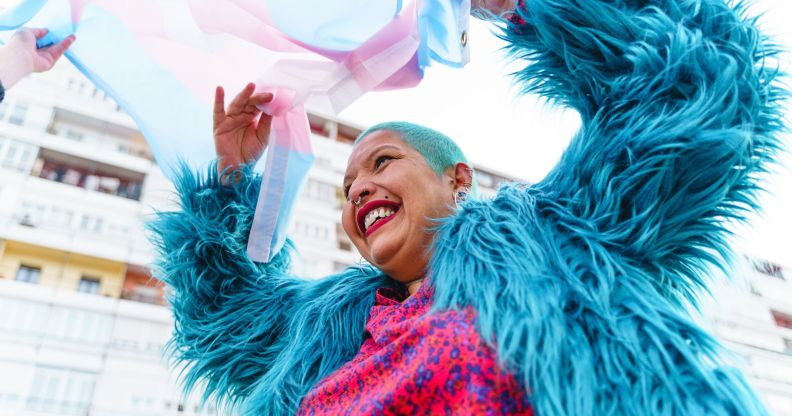 A person happily waving a trans flag.