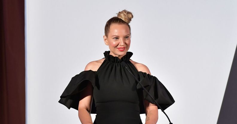 Singer Sia on a stage in a black dress smiling