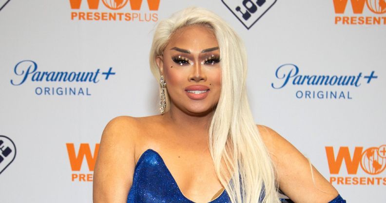 Jiggly Caliente in blonde hair and a blue dress smiling at a red carpet event in 2022.