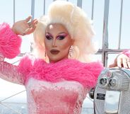 The Vivienne at the top of the empire state building in a pink outfit.