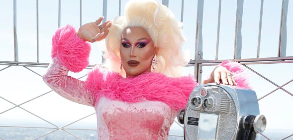 The Vivienne at the top of the empire state building in a pink outfit.