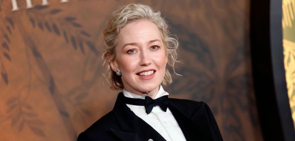 Carrie Coon at the White Lotus premiere in a suit and bow tie against a brown backdrop.