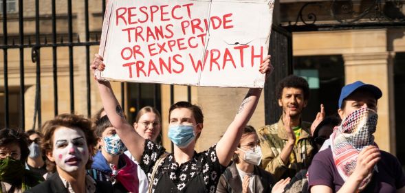 Protester holds up sign reading "Respect trans pride or expect trans wrath"