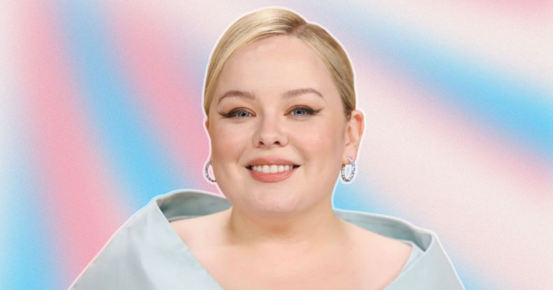 Nicola Coughlan with coiffed blonde hair and a baby blue shoulder piece. She is smiling. Her photo is against a blue pink and white background, reflecting the trans flag colours.