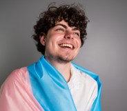 Transgender male wrapped in a transgender flag contemplating on a studio shot