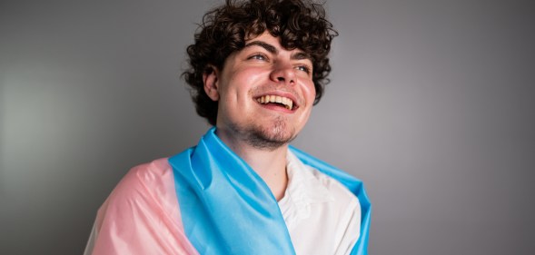 Transgender male wrapped in a transgender flag contemplating on a studio shot