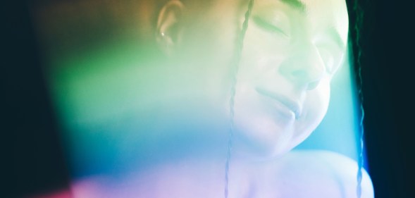 Rainbow colored light refracting onto the face of a woman. (Getty)