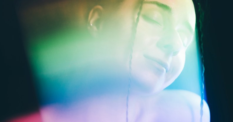 Rainbow colored light refracting onto the face of a woman. (Getty)