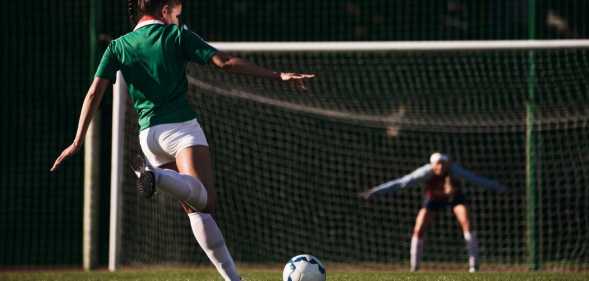 Two female soccer players with soccer ball playing on soccer field. Penalty shot.