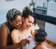 High angle view of cheerful lesbian mothers playing with adopted son in living room at home.