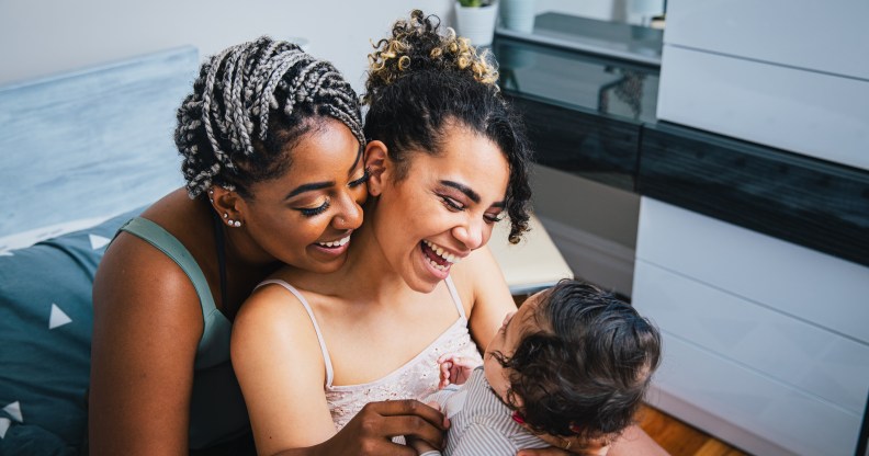 High angle view of cheerful lesbian mothers playing with adopted son in living room at home.