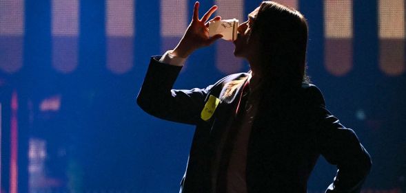 Tommy Cash drinking a coffee on stage during his Eurovision performance for Estonia