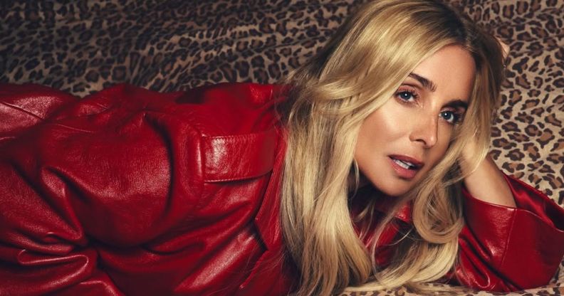 Louise Redknapp in a red jacket posing on a leopard print bed.