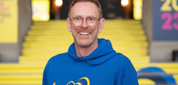 Martin Green standing in front of the Eurovision building, in a blue Eurovision hoodie.