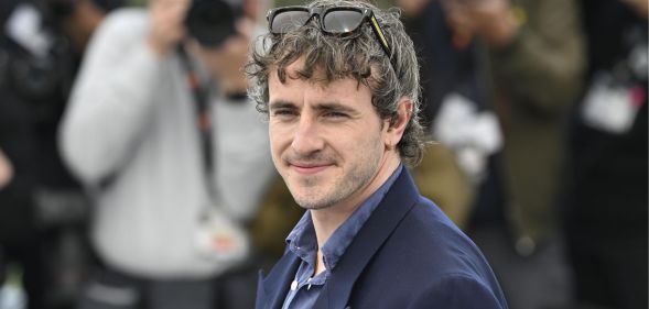 Paul Mescal on the red carpet at Cannes Film Festival squinting and smiling.
