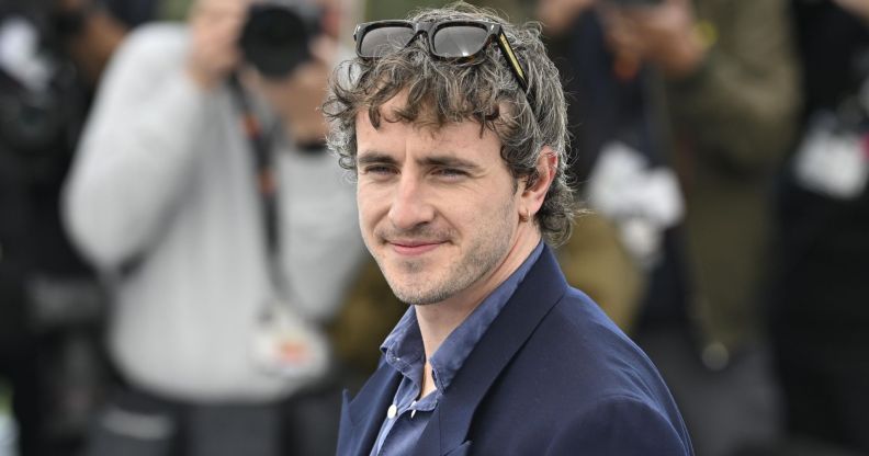 Paul Mescal on the red carpet at Cannes Film Festival squinting and smiling.